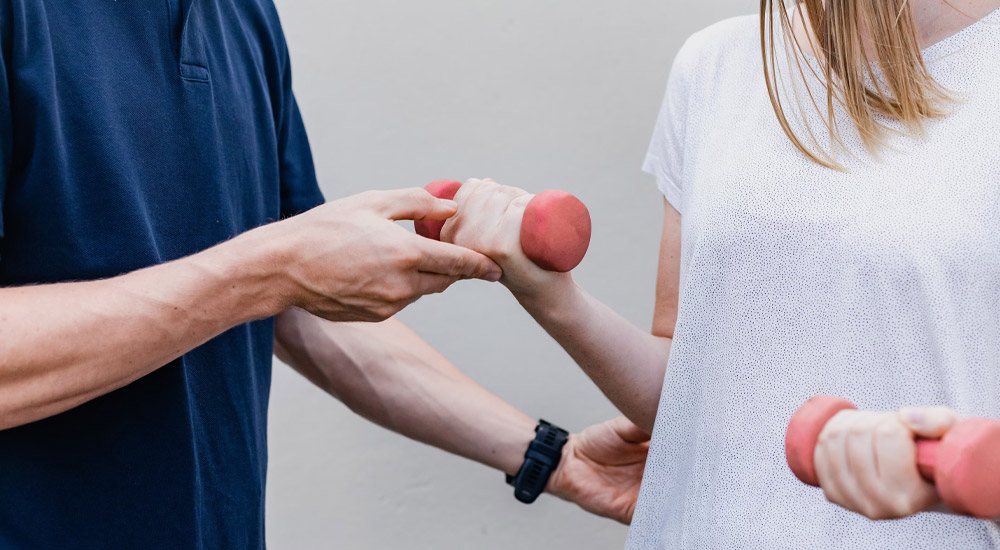 Shows a young woman weight-training, relating to Nutritional Approaches for Recovery Without Walls patients